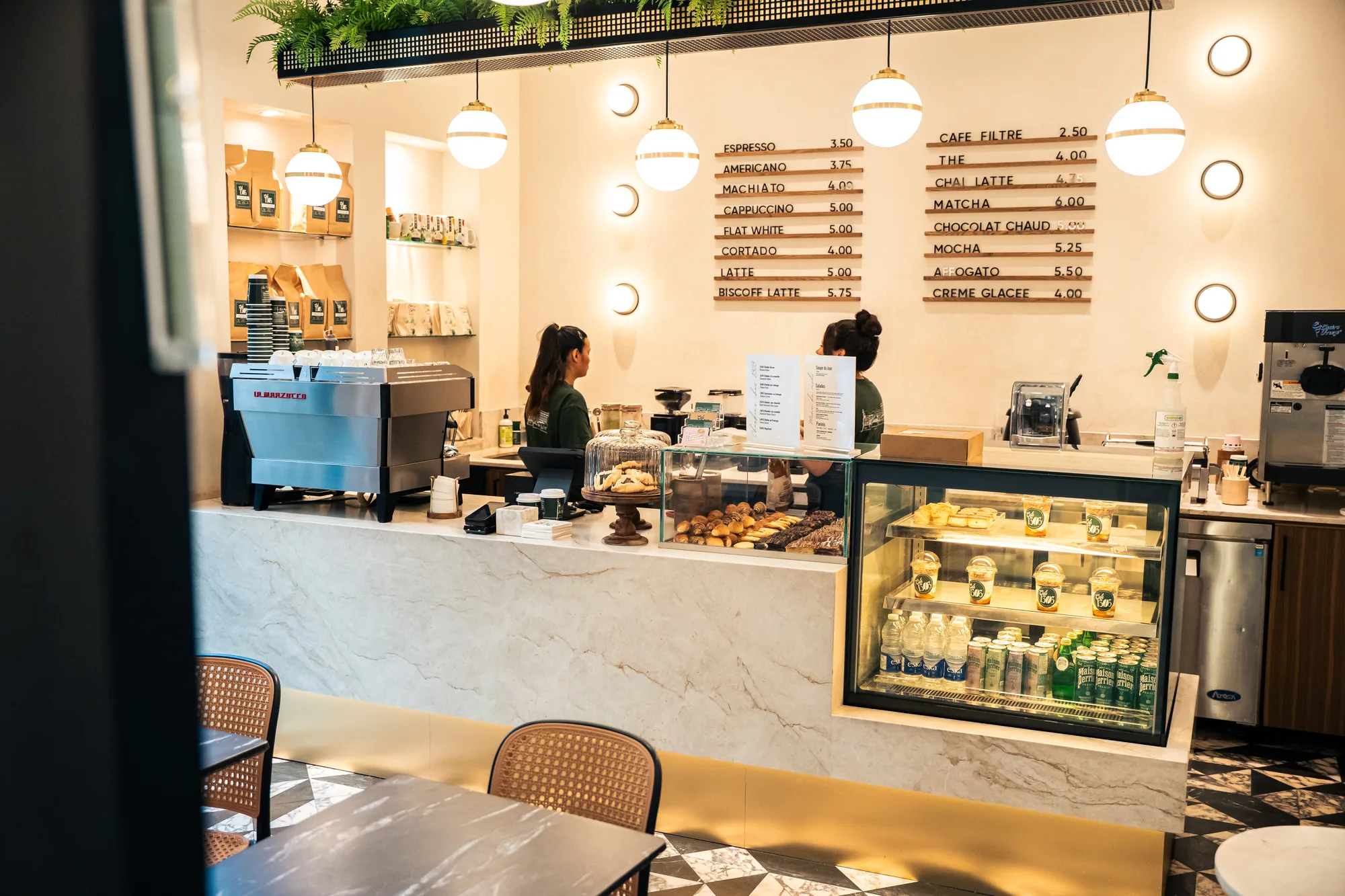 Behind the marble counter at the café on Greene Avenue, the menu board and pastry case ready before the cars arrive.